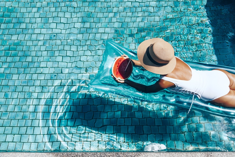 Girl floating on beach mattress and eating watermelon in the blue pool. Girl floating on beach mattress and eating watermelon in the blue pool.