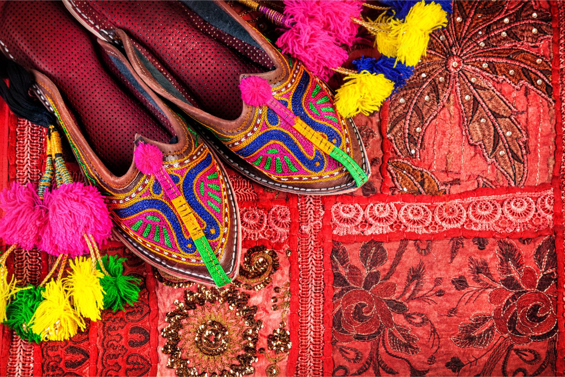 Colorful ethnic shoes and camel decorations on red Rajasthan cushion cover on flea market in India